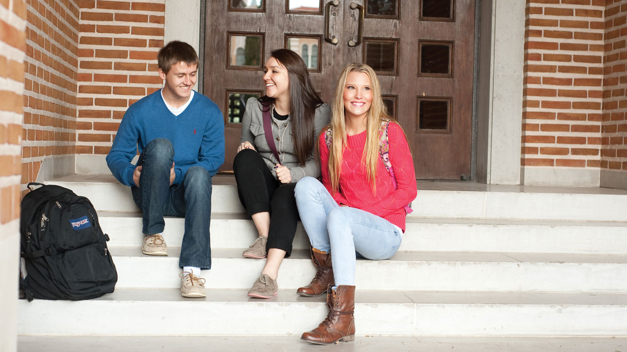 Students sitting on the steps of a building. 